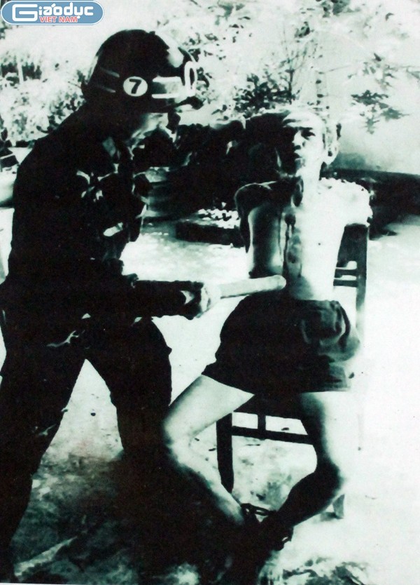 Một chiến sĩ cộng sản đang bị một tên cai ngục ở đảo Phú Quốc dùng "gậy biệt li" do Bảy Nhu nghĩ ra để tra tấn